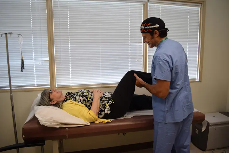 Doctor with a patient laying back on an exam table having her knee examined. 