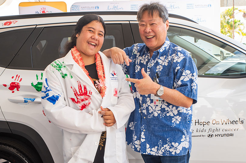 Two people in front of vehicle 