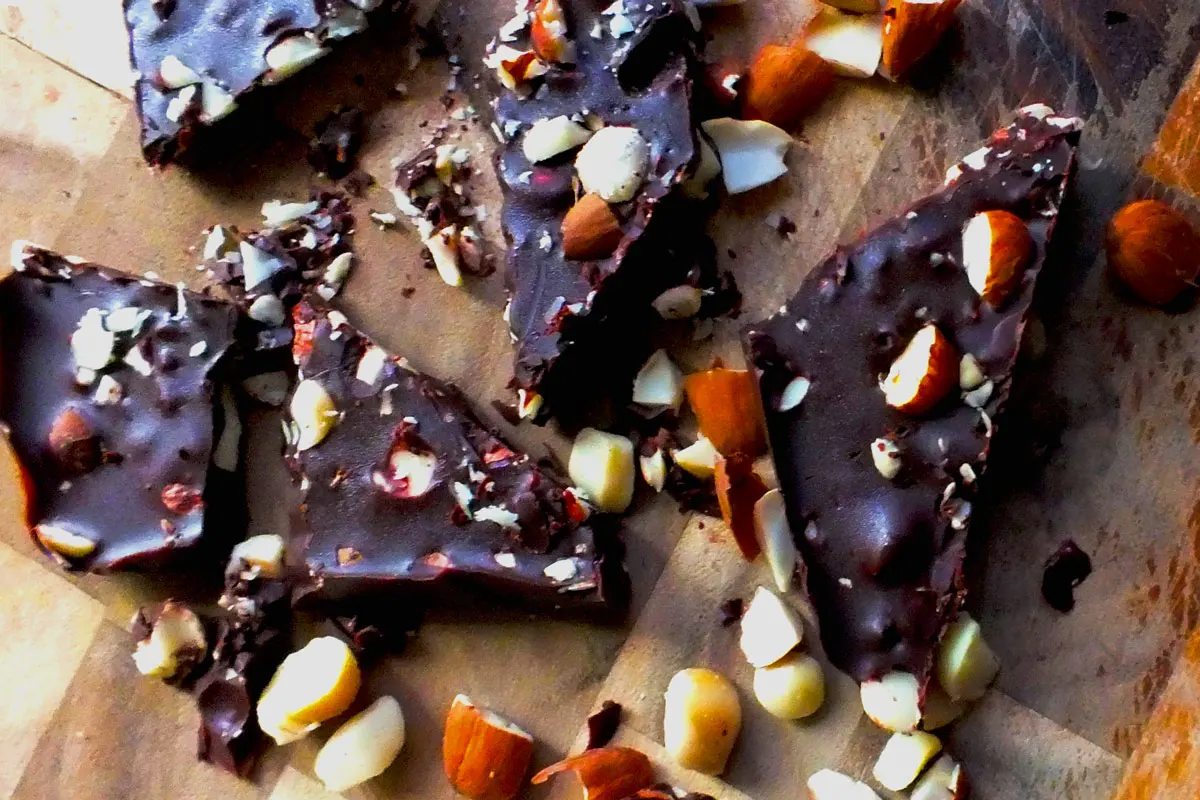 Pieces of nut-filled chocolate with nut pieces scattered around.