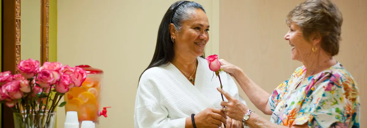 Female patient in a cotton robe receiving a rose from a provider after her mammogram.