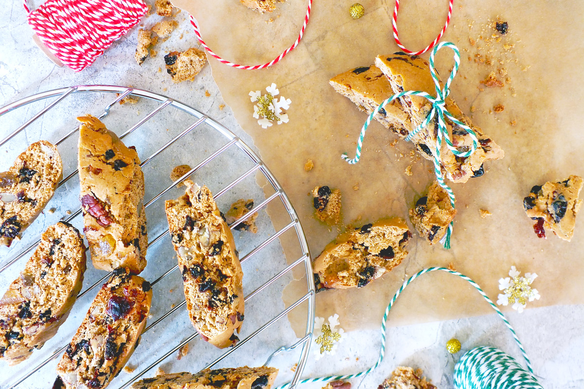 Holiday biscotti on a cooling rack with some festive twine and decorations in the background.