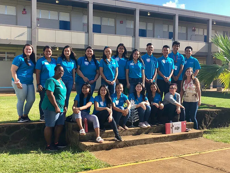 Group shot of medical assistant students in blue polo shorts outside of a local high school.