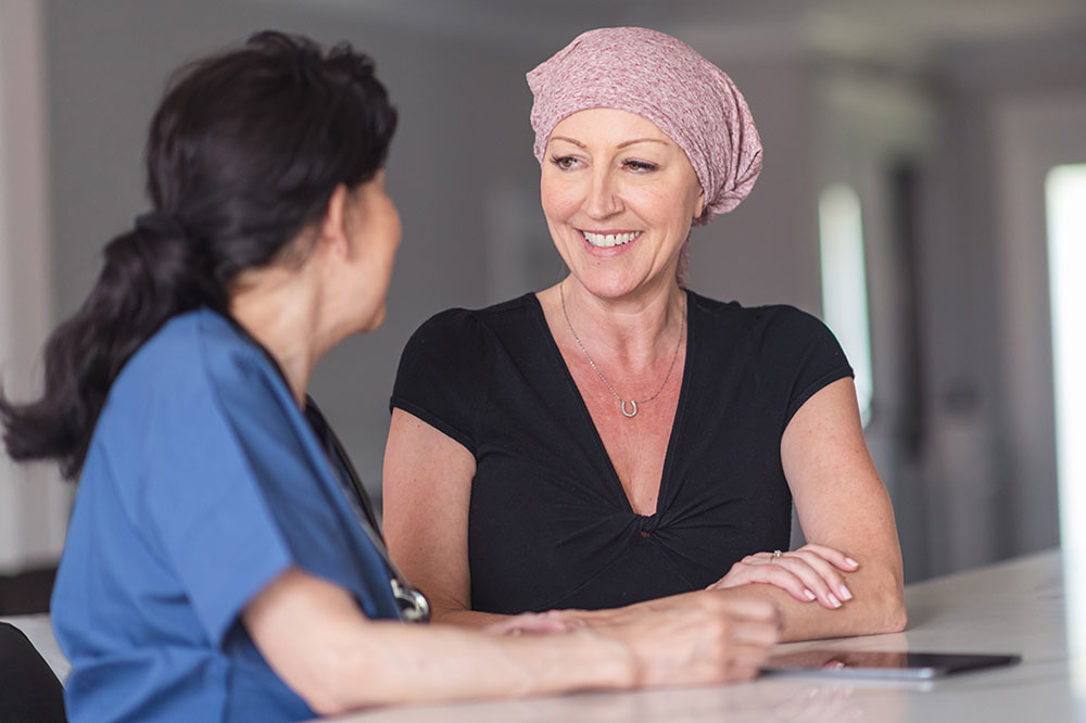 A woman wearing a headwrap meets with her cancer care team patient navigator.